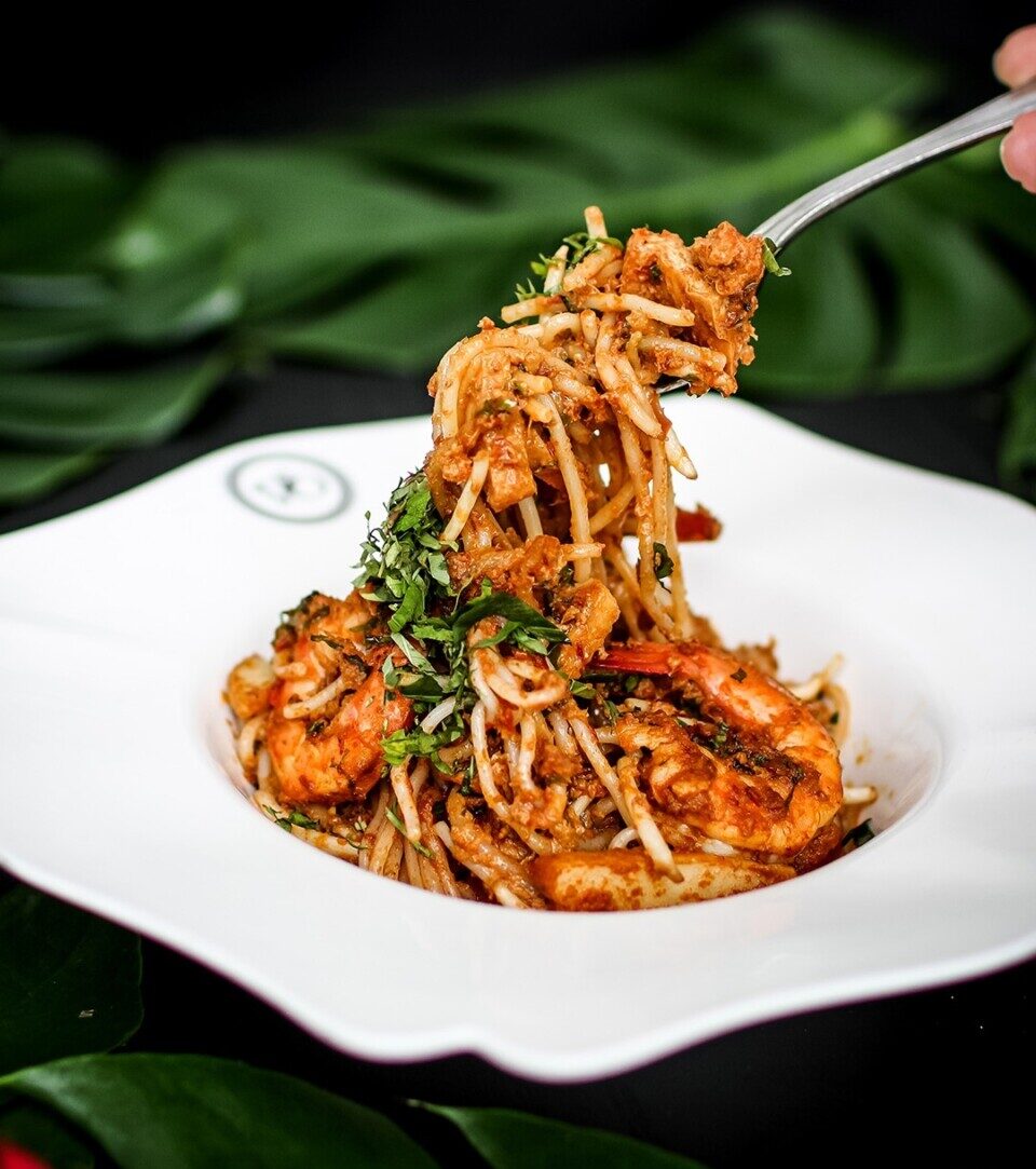 Indulge in Violet Oon's dry laksa: a vibrant mix of textures and flavors, featuring succulent prawns and a rich, aromatic gravy!